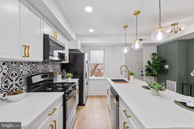 kitchen with sink, light hardwood / wood-style flooring, decorative light fixtures, white cabinetry, and stainless steel appliances