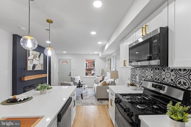 kitchen with light hardwood / wood-style flooring, pendant lighting, decorative backsplash, white cabinets, and appliances with stainless steel finishes