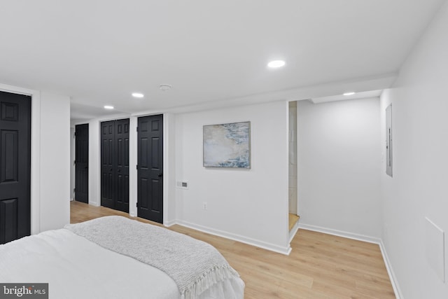 bedroom with light hardwood / wood-style flooring and multiple closets