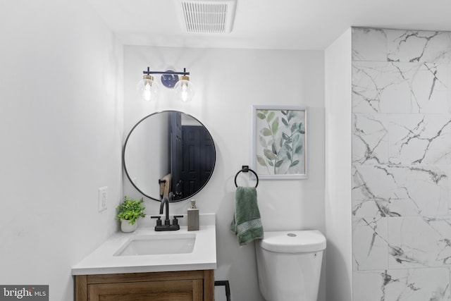 bathroom featuring a tile shower, vanity, and toilet