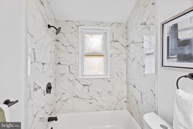 bathroom featuring tiled shower / bath combo and toilet