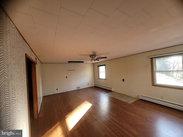 empty room with ceiling fan, hardwood / wood-style floors, and a baseboard heating unit