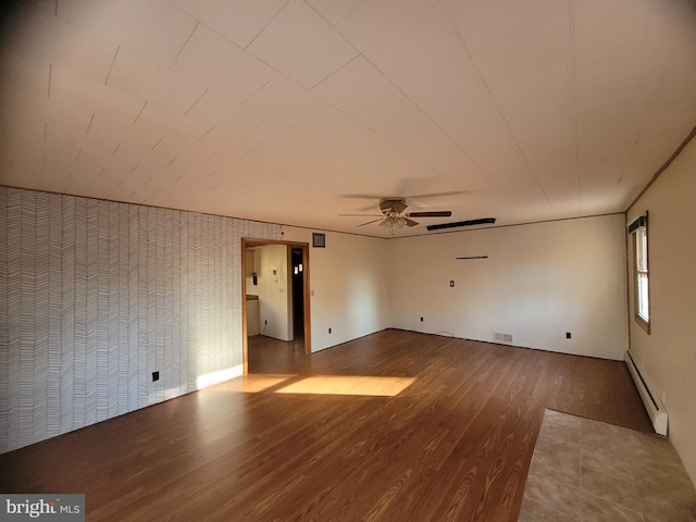 unfurnished room featuring ceiling fan, wood-type flooring, and a baseboard heating unit