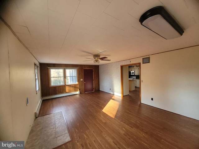 unfurnished room with dark hardwood / wood-style flooring, baseboard heating, and ceiling fan