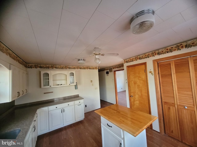 kitchen with a center island, butcher block counters, dark wood-type flooring, ceiling fan, and white cabinetry