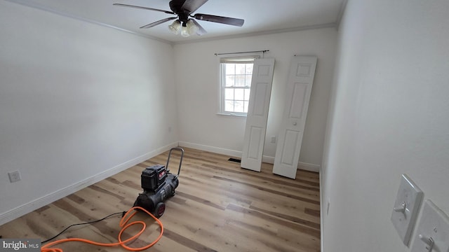 interior space featuring ceiling fan, crown molding, baseboards, and wood finished floors