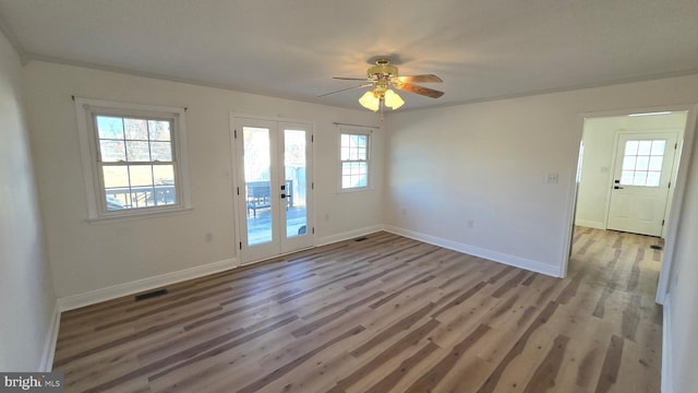 empty room with baseboards, visible vents, ceiling fan, wood finished floors, and french doors