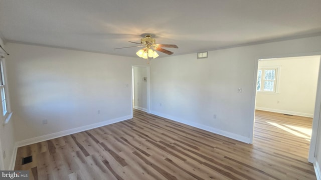 spare room featuring light wood-style floors, baseboards, visible vents, and a ceiling fan