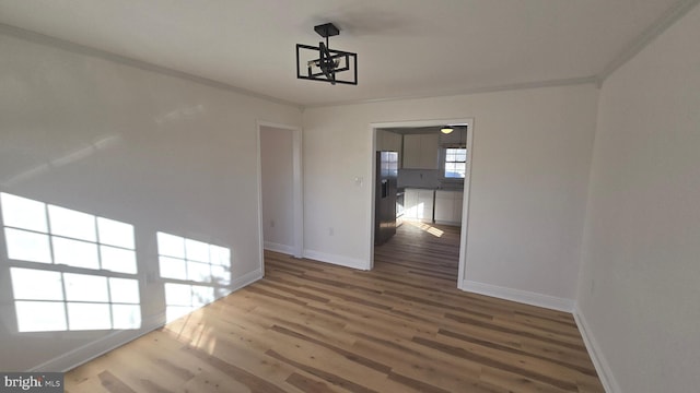 unfurnished dining area with ornamental molding, baseboards, and wood finished floors