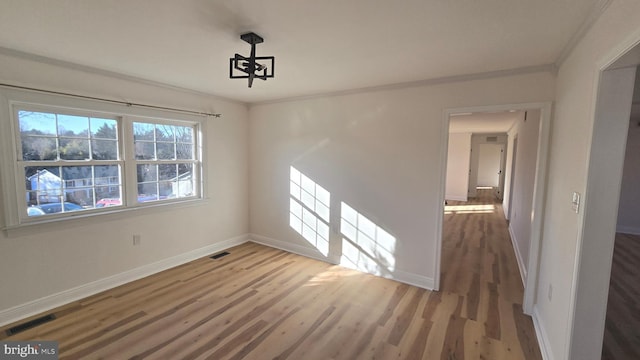 spare room with ornamental molding, wood finished floors, and baseboards