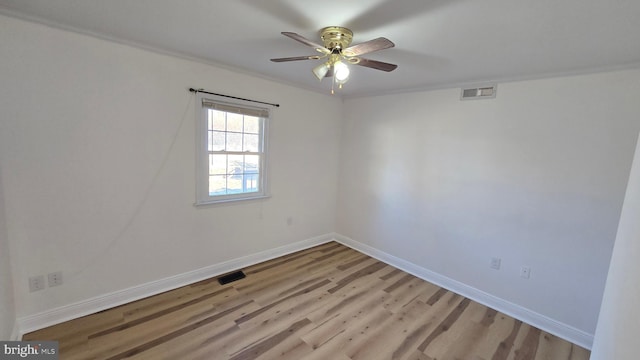 empty room featuring light wood finished floors, a ceiling fan, visible vents, and baseboards