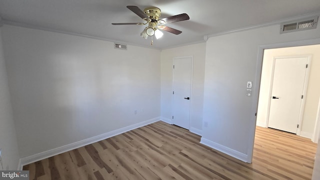 unfurnished room featuring ornamental molding, baseboards, visible vents, and light wood finished floors