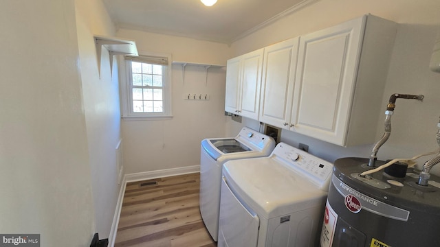 washroom featuring light wood-style floors, water heater, washer and dryer, ornamental molding, and cabinet space