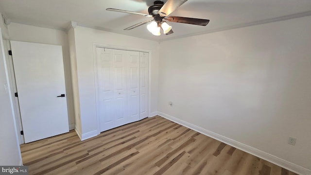 unfurnished bedroom featuring a closet, ornamental molding, a ceiling fan, light wood-type flooring, and baseboards