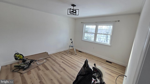 interior space featuring crown molding, wood finished floors, visible vents, and baseboards