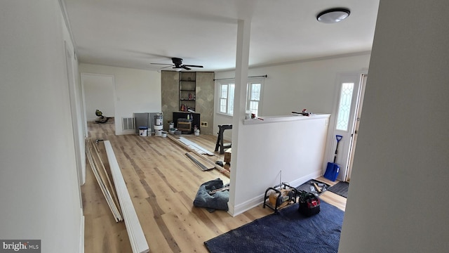 interior space featuring a ceiling fan, visible vents, baseboards, and wood finished floors