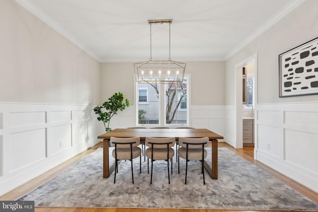 dining area with ornamental molding, a chandelier, and light hardwood / wood-style floors