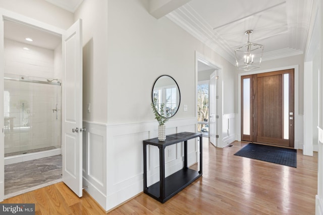 foyer entrance featuring hardwood / wood-style flooring, ornamental molding, and a notable chandelier