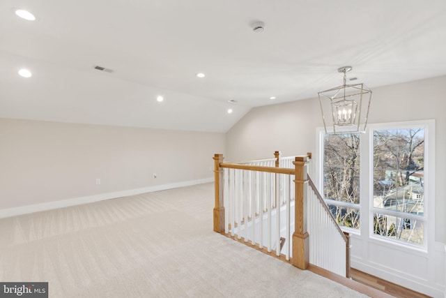 corridor featuring lofted ceiling, light carpet, and a chandelier