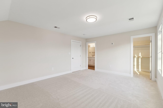 unfurnished bedroom featuring light carpet and ensuite bathroom