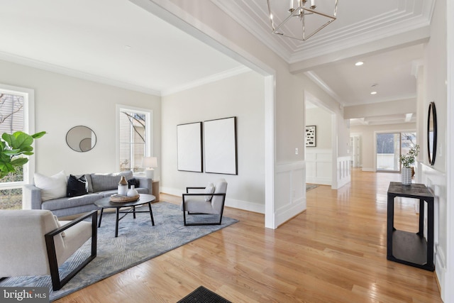 living room with ornamental molding, a chandelier, and light hardwood / wood-style flooring