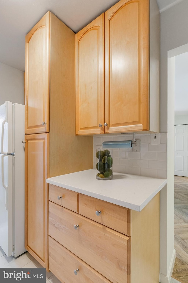 kitchen with decorative backsplash, white fridge, light brown cabinetry, and light parquet floors