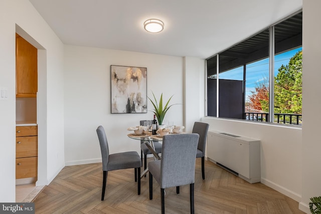 dining space featuring radiator heating unit and light parquet floors