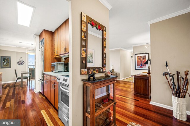 kitchen featuring dark hardwood / wood-style floors, ornamental molding, and appliances with stainless steel finishes