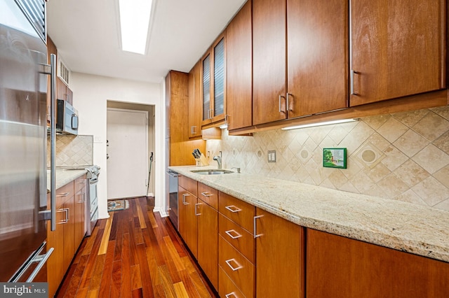 kitchen with light stone countertops, appliances with stainless steel finishes, tasteful backsplash, sink, and dark hardwood / wood-style floors