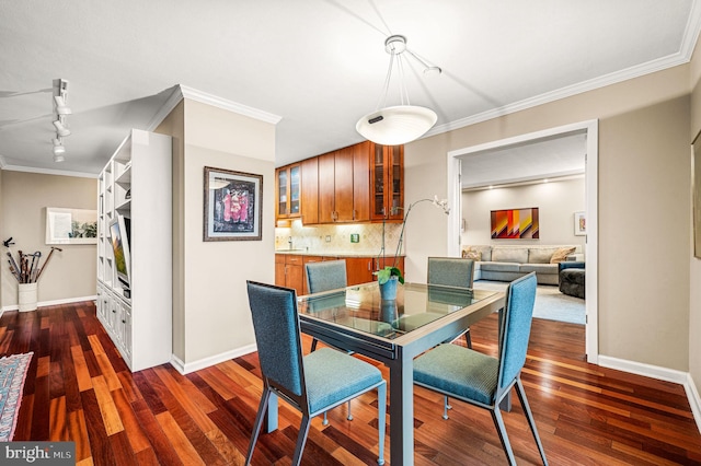 dining space featuring dark hardwood / wood-style floors, ornamental molding, and rail lighting