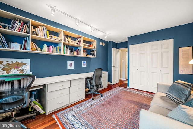 office area featuring built in desk, dark wood-type flooring, and track lighting