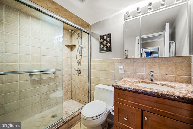 bathroom featuring a shower with door, vanity, tile walls, and toilet