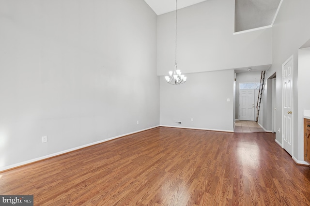 interior space with high vaulted ceiling, an inviting chandelier, and hardwood / wood-style floors