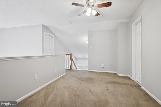 additional living space with vaulted ceiling, ceiling fan, a textured ceiling, and carpet floors