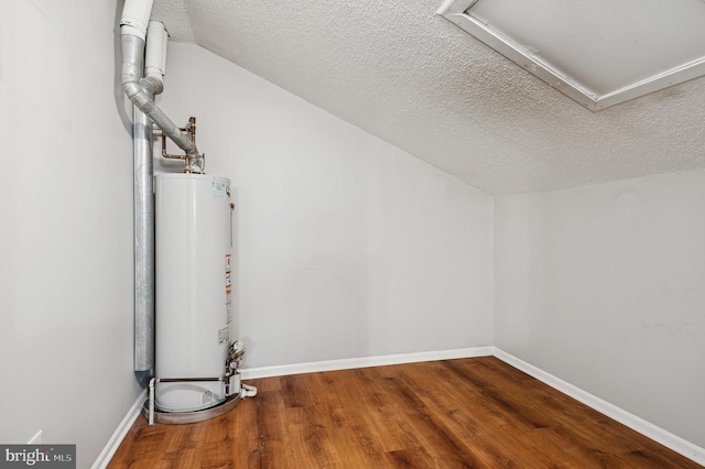 additional living space featuring lofted ceiling, water heater, a textured ceiling, and hardwood / wood-style flooring