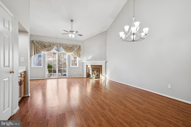 unfurnished living room with ceiling fan with notable chandelier, hardwood / wood-style flooring, and a fireplace