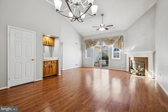 unfurnished living room featuring high vaulted ceiling, a tiled fireplace, ceiling fan with notable chandelier, and wood-type flooring