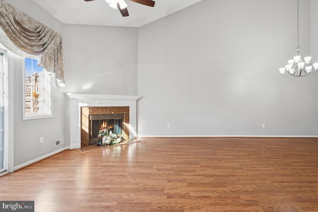 unfurnished living room featuring ceiling fan with notable chandelier, hardwood / wood-style floors, and a tile fireplace