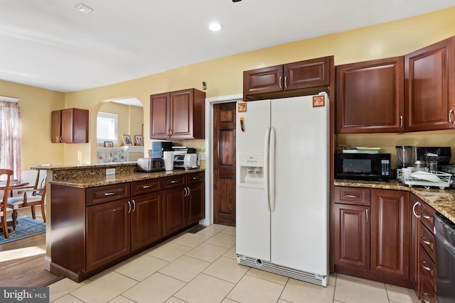 kitchen featuring light stone countertops, white fridge with ice dispenser, stainless steel dishwasher, kitchen peninsula, and light hardwood / wood-style floors