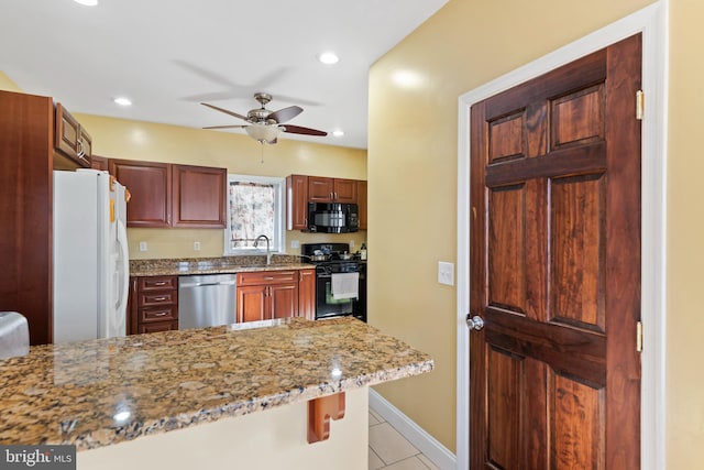 kitchen with ceiling fan, a kitchen breakfast bar, light stone counters, kitchen peninsula, and black appliances