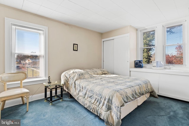 bedroom with dark colored carpet, a closet, multiple windows, and ornamental molding