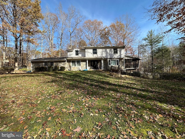 rear view of house featuring a sunroom and a lawn