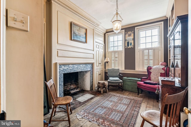 living area with wood-type flooring, crown molding, a high end fireplace, and a chandelier