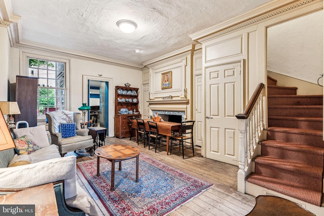 living room with crown molding, a textured ceiling, and light wood-type flooring