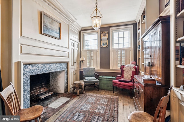 sitting room featuring an inviting chandelier, dark hardwood / wood-style flooring, ornamental molding, and a premium fireplace