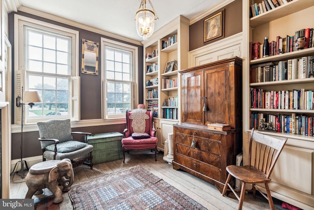 sitting room featuring a chandelier, wood-type flooring, built in shelves, and ornamental molding