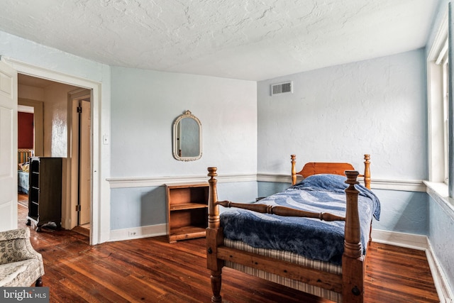 bedroom with dark hardwood / wood-style floors and a textured ceiling