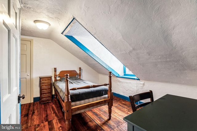 bedroom with a textured ceiling, dark hardwood / wood-style floors, and lofted ceiling with skylight