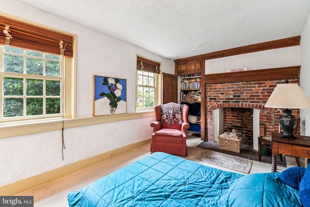 bedroom featuring carpet flooring, a textured ceiling, and a brick fireplace