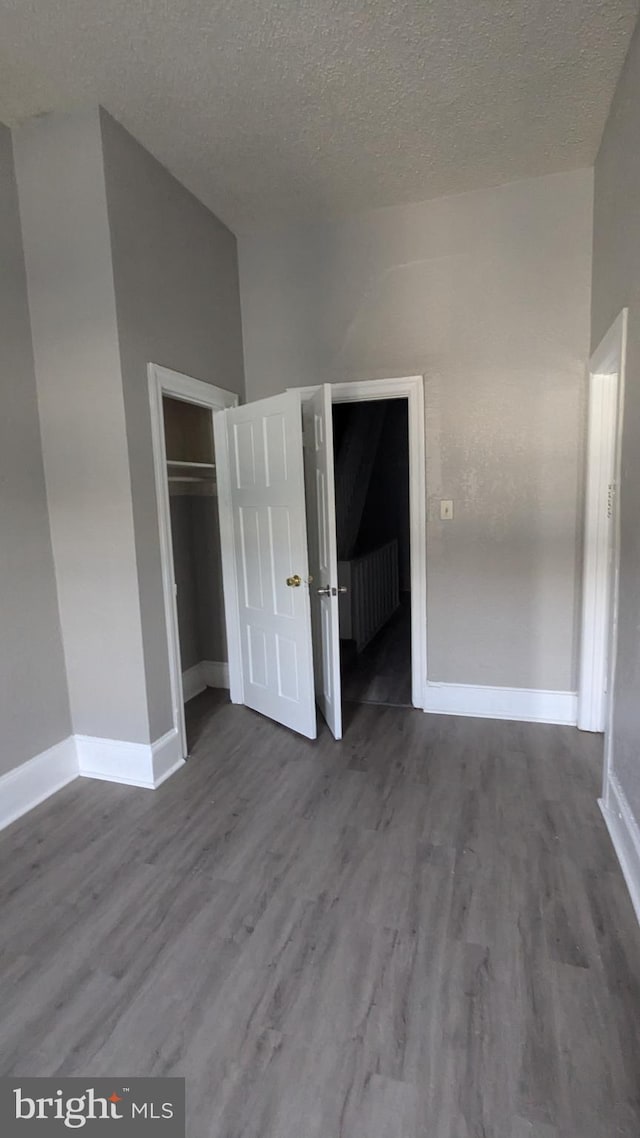 unfurnished bedroom featuring a closet, wood-type flooring, and a textured ceiling